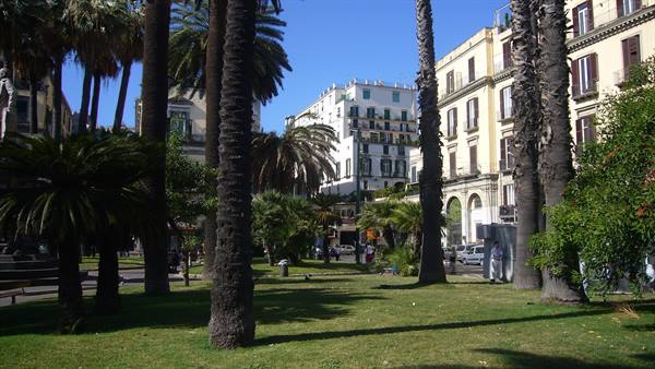 Palms and buildings in Naples Villa Comunale park, bright sunlight