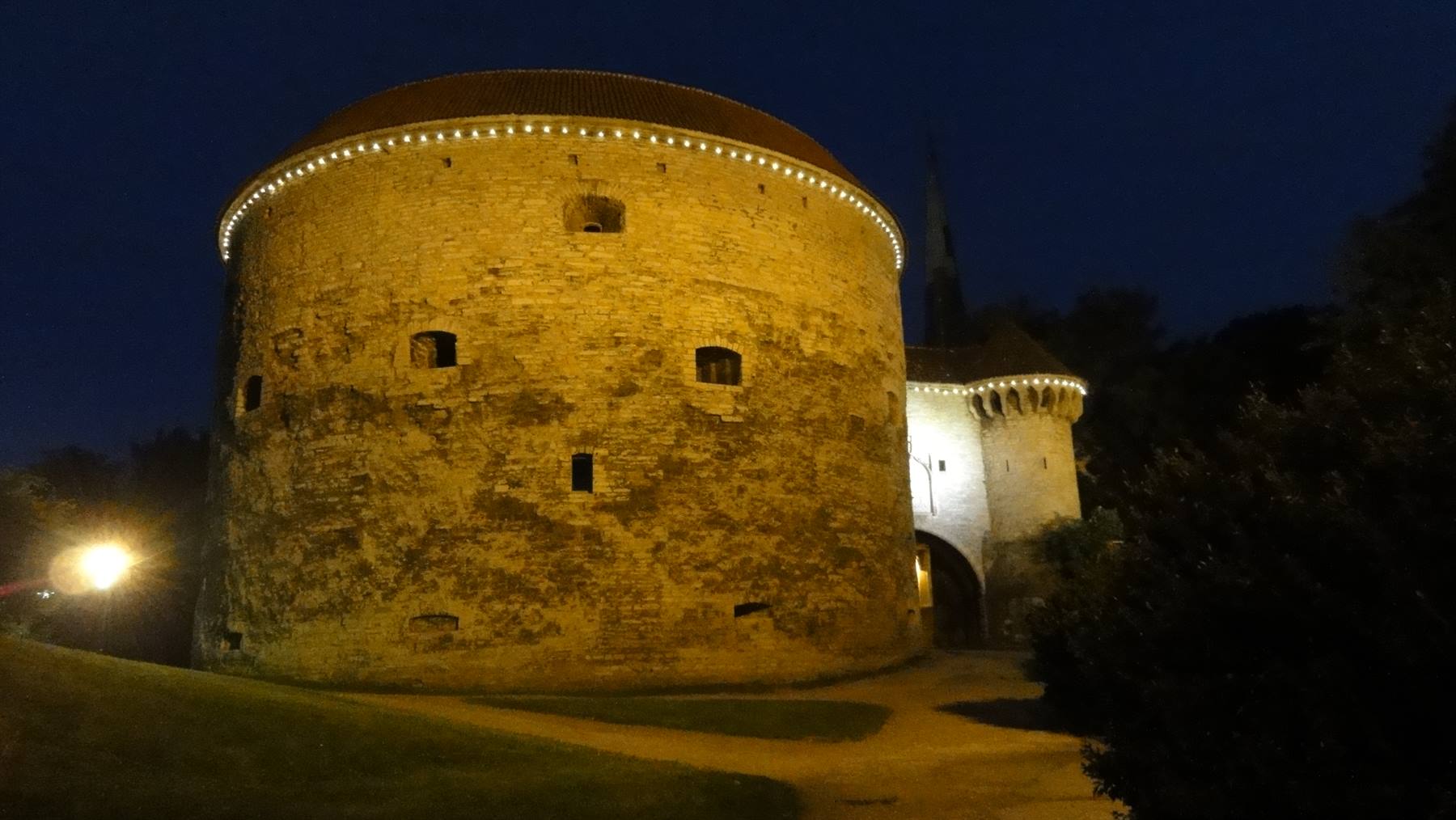 La torre Grassa illuminata di notte a Tallinn, mura medievali in pietra