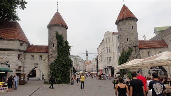 Viru Gate in Tallinn: medieval stone towers with red roofs, tourists strolling by