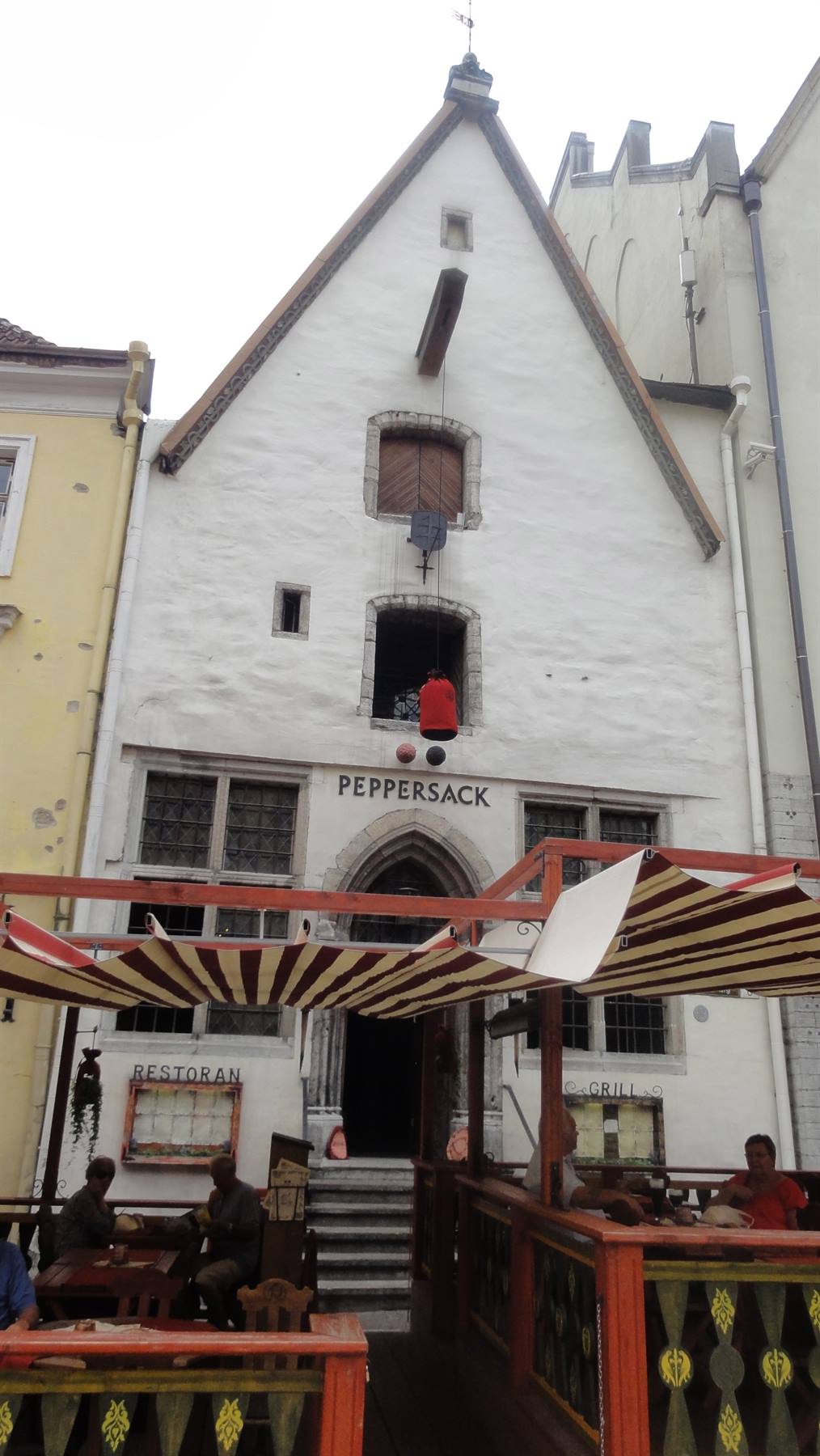 Facciata bianca medievale del ristorante Peppersack con tende a strisce