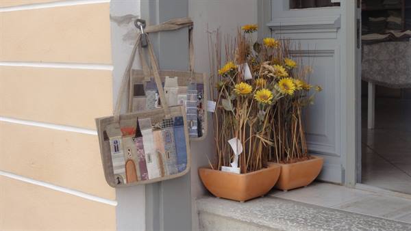 Fabric bags with painted houses hanging beside pots of dried sunflowers
