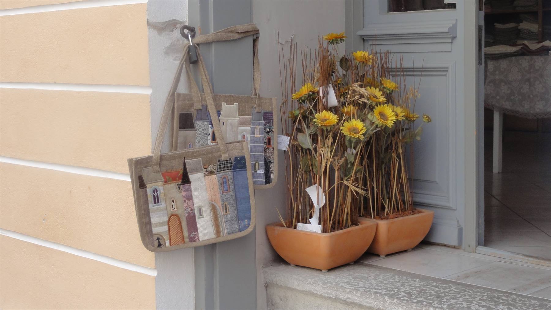 Borse in tessuto con case dipinte appese accanto a vasi di girasoli secchi