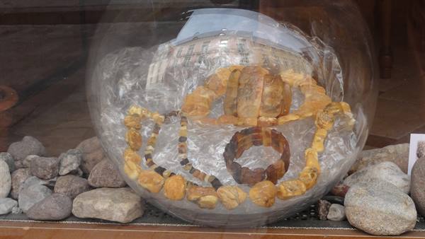 Amber bracelets and necklaces in a shop window with stones and glass sphere