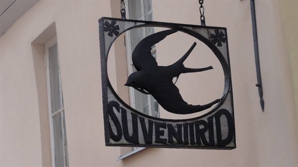 Wrought iron sign with a swallow and Suveniirid hanging by chains