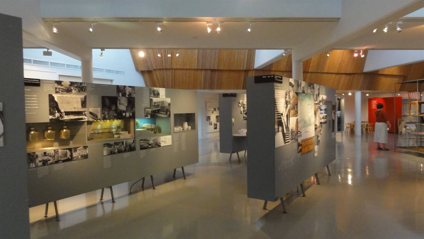 Pannelli espositivi grigi con foto e oggetti in un museo luminoso di legno