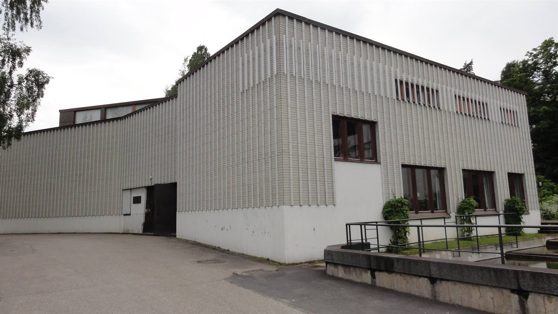 Edificio modernista rivestito di piastrelle bianche tra alberi, luce diffusa