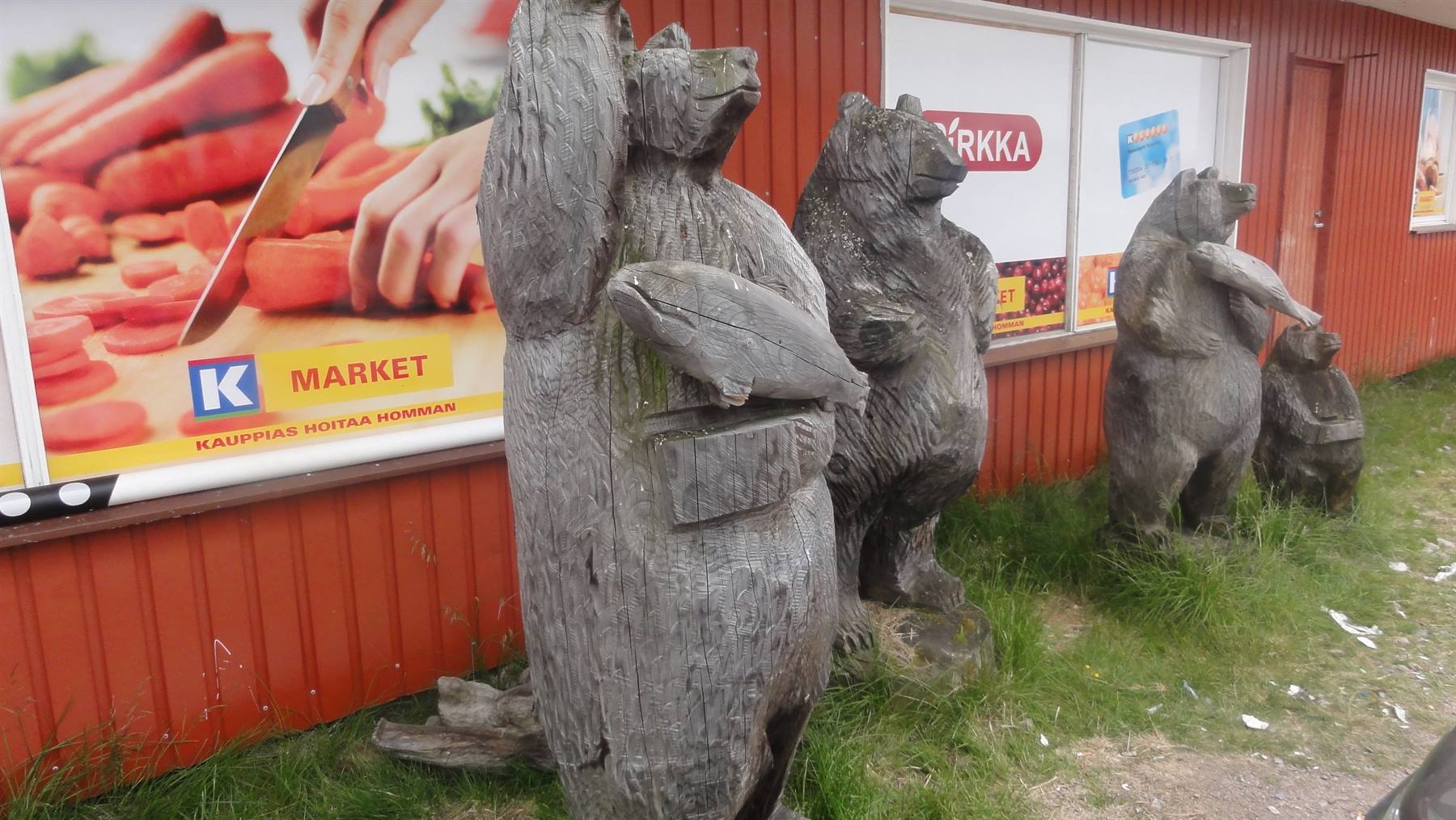 Sculture di orsi in legno con pesci davanti a un market