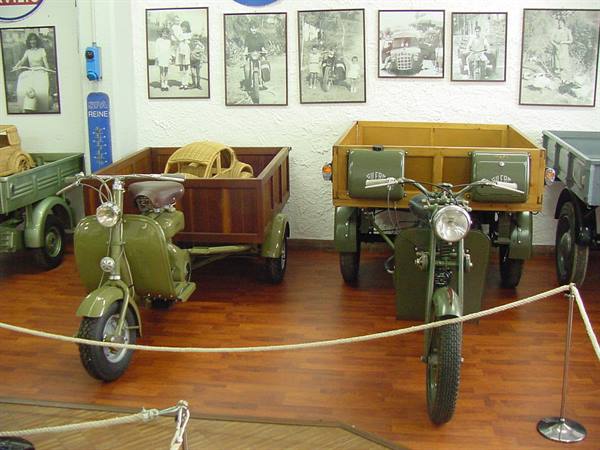 Vintage three-wheeled motorcycles with wooden cargo beds displayed in a museum