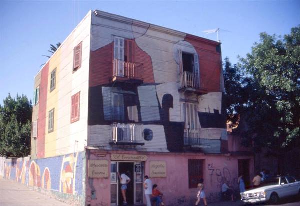 Colorfully painted house with balconies in La Boca, Buenos Aires, people and car outside