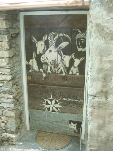 Wooden door painted with goats and Raimonda Pedori sign, between stone walls