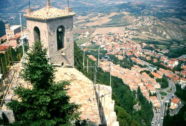 Stone bell tower in San Marino above red-roofed houses