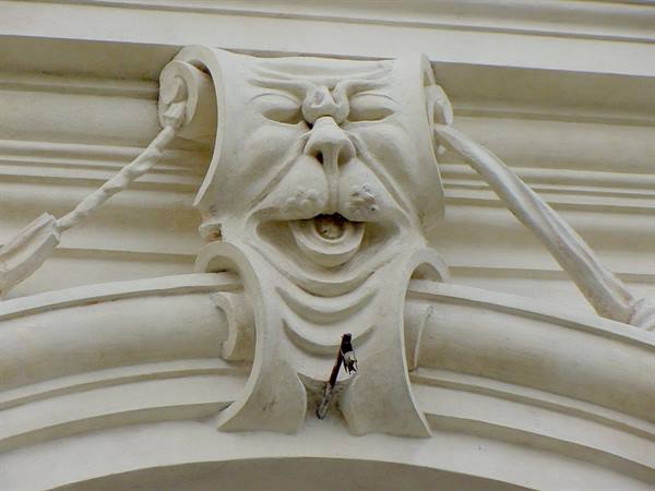 Grotesque stone mask carved above a window, with braided rope detail