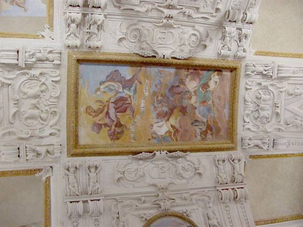 Ceiling with gold-framed fresco and white baroque stucco, natural light