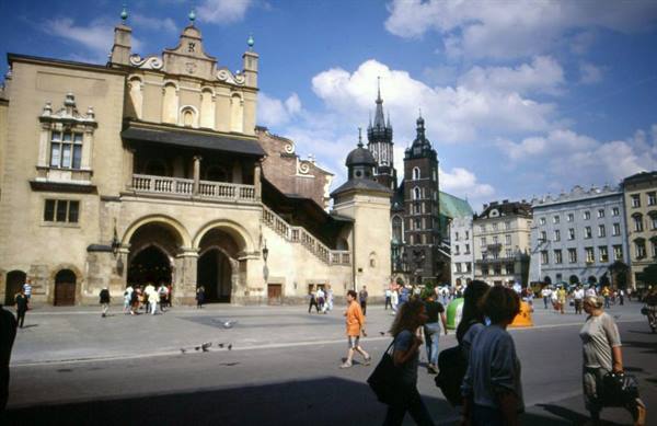 Tourists walking past the Cloth Hall and St Mary's Basilica in Kraków