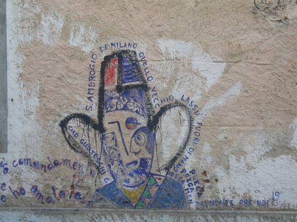 Mural on plastered wall: stylized blue face with hat and writings