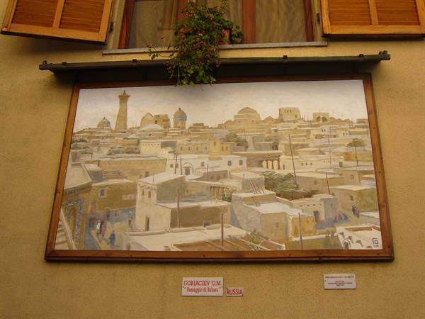Painted artwork of rooftops and minaret beneath wooden-shuttered window