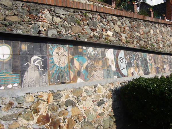 Painted ceramic tile mural with sun and moon on stone wall