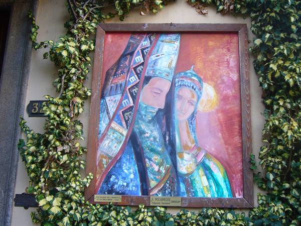 Framed painting of two veiled figures hanging on an ivy-covered wall