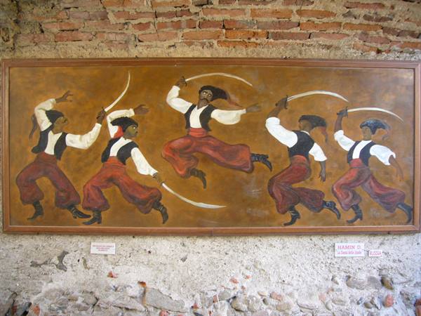 Painting of dancers with curved swords, hung on a brick wall