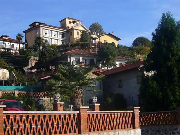 Hillside villas with terracotta roofs, palms and perforated brick fence