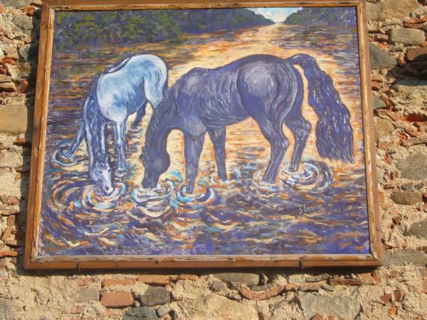 Painting of two horses drinking in a river, framed on a stone wall