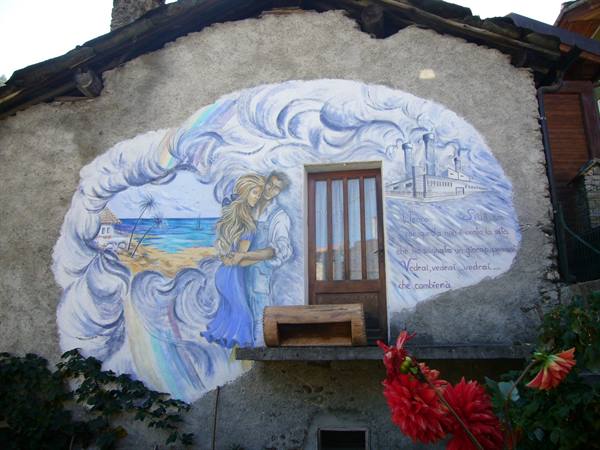 Mural on stone facade: embracing couple, sea and factory painted around a wooden door