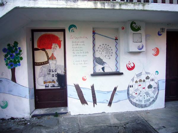 Colorful mural with tree, peacock and painted village on white facade