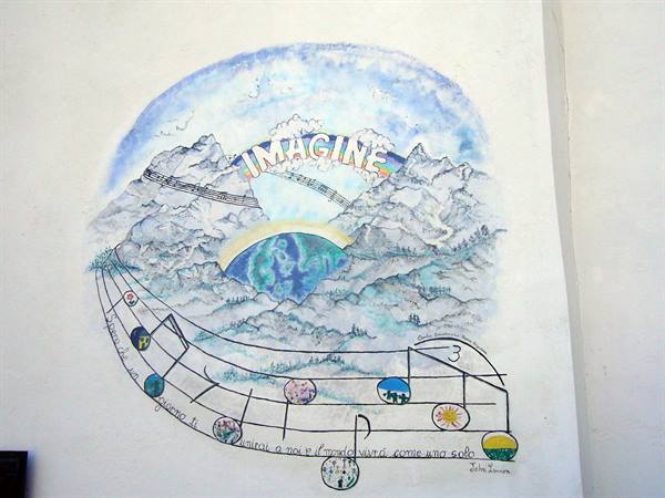 Mural with the word Imagine, painted mountains and colorful music staff on white wall