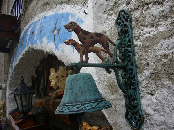 Green cast iron bell with metal dogs on a frescoed wall