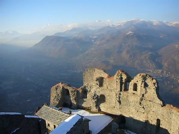 Stone ruins of Sacra di San Michele with snow and hazy mountains behind