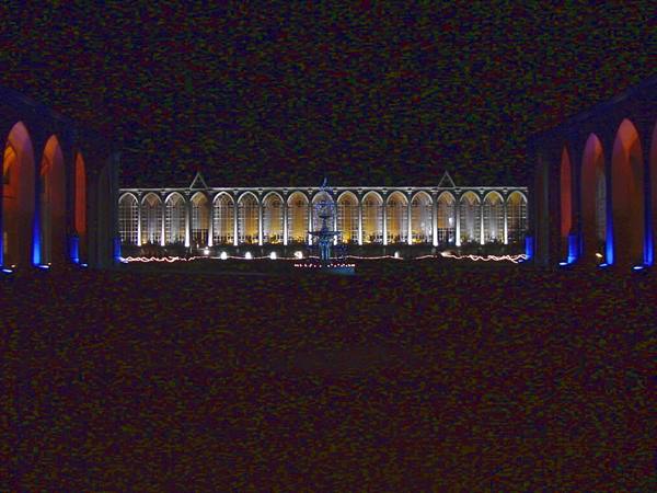 Illuminated arcade at night, blue-golden gothic arches, dark stone courtyard in front