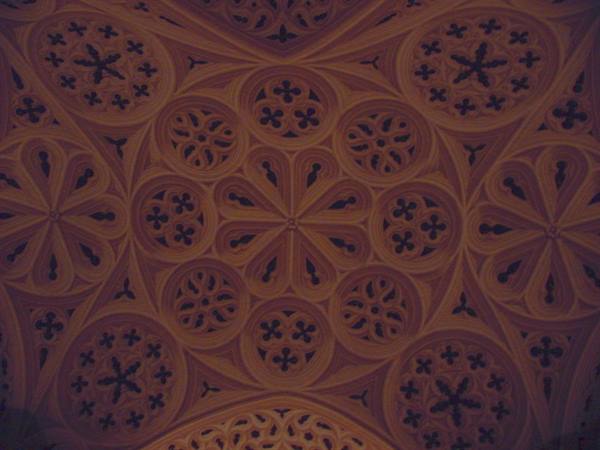 Stone vault with carved Gothic rosettes under warm amber light