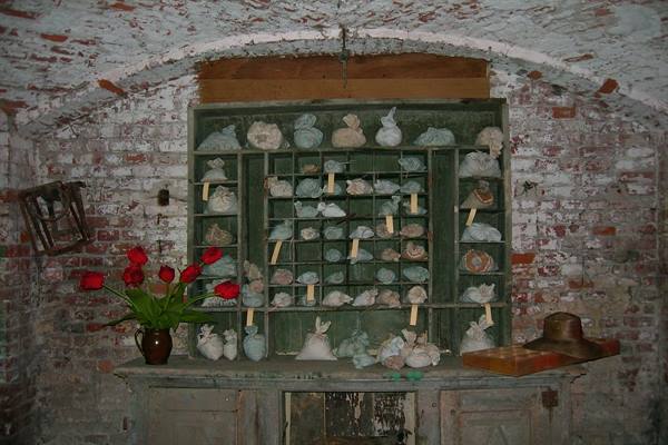 Green shelving with cloth sacks, red tulips and hat in pile