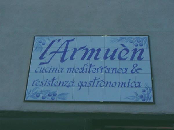 Blue ceramic tile sign on wall: L'Armuen restaurant, Mediterranean cuisine