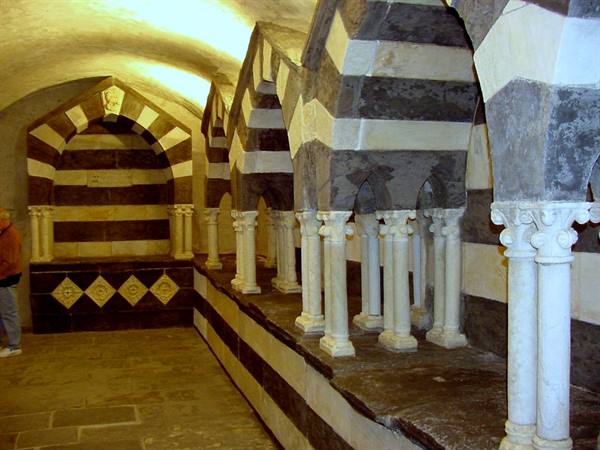 Hall with striped black-and-white arches on small marble columns, warm artificial light