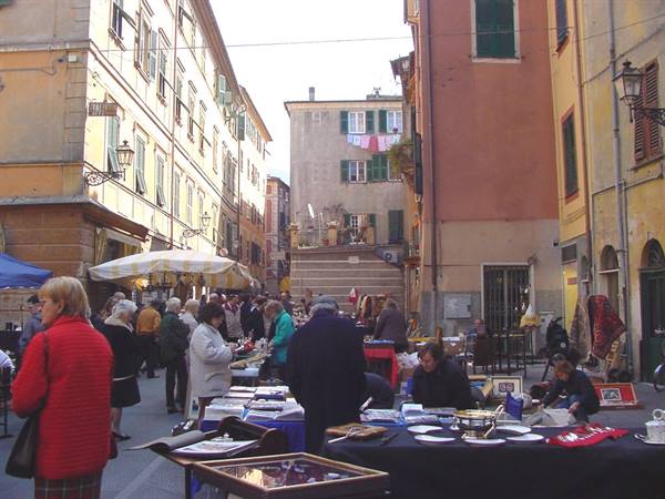 Flea market between colorful old buildings, people browsing stalls