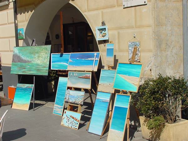 Seaside paintings displayed on easels under a stone arch