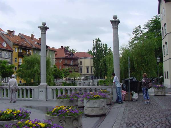 Cobbler's Bridge in Ljubljana, stone columns, flower planters and pedestrians