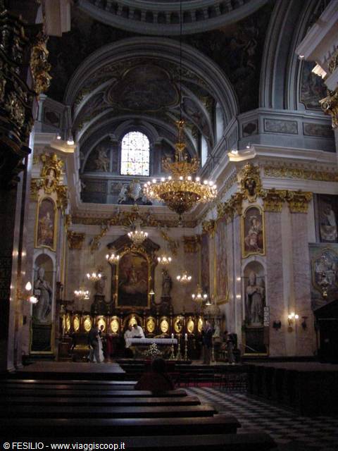 Baroque church interior with gilded altar, chandelier and worshippers praying