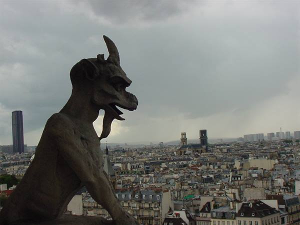 Stone gargoyle on Notre-Dame cathedral watches over Paris under cloudy skies