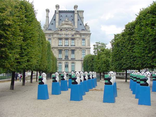 Panda sculptures on blue pedestals in the Tuileries garden, Louvre behind