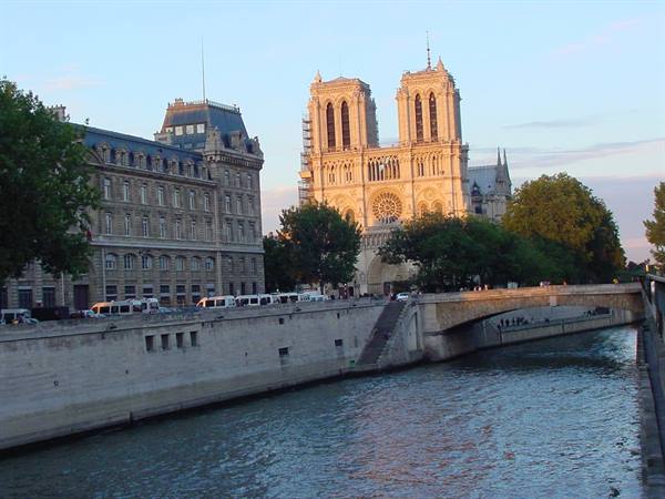 Notre-Dame Cathedral at dusk with the Seine and a stone bridge