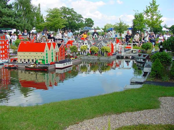 Lego brick houses by a canal at Madurodam, visitors watching around