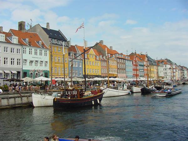 Nyhavn in Copenhagen: historic wooden boats moored beside colorful townhouses and cafes