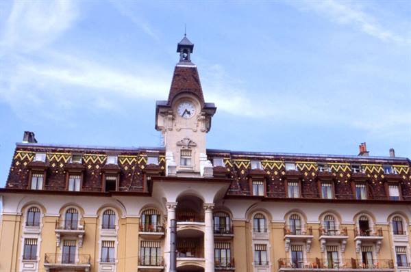 Yellow historic building with clock tower and patterned tiled roof