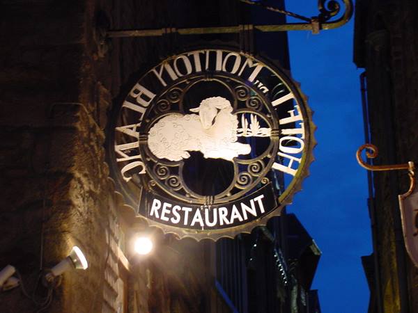 Wrought-iron sign of Hotel Le Mont Blanc, lit sheep against blue sky