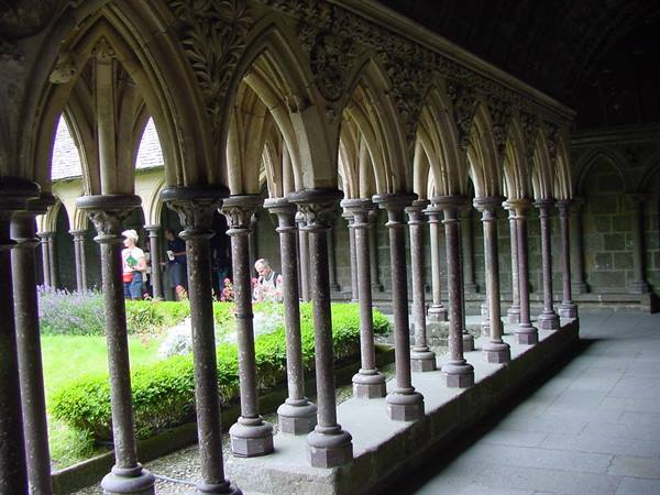 Gothic stone cloister with carved arches and columns, visitors in the garden, Mont-Saint-Michel