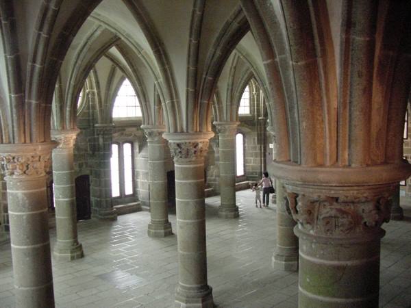 Gothic hall with granite pillars and ribbed vaults, a visitor walking through