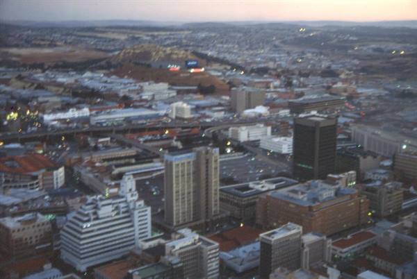 Johannesburg skyscrapers at dusk, lights on, hills in background
