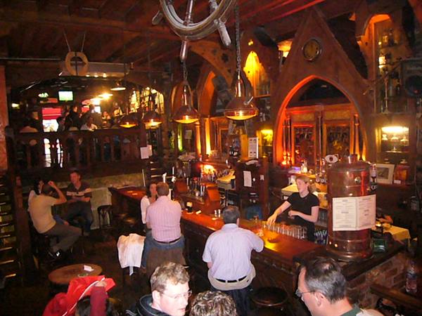 Wooden pub with golden lamps, bartender pouring beer for customers
